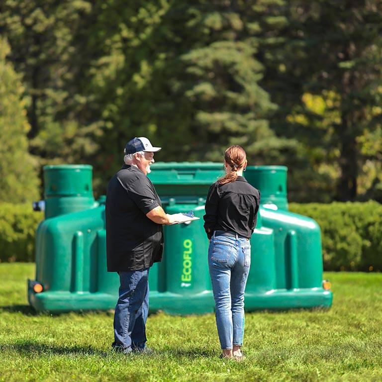 Two people in front of an Ecoflo biofilter